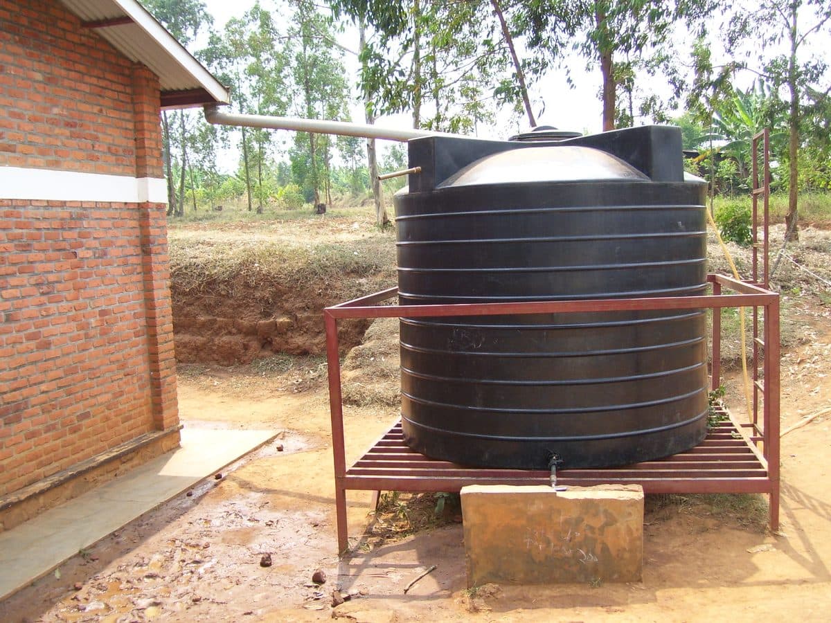 Rooftop rainwater harvesting tank collecting water beside a home